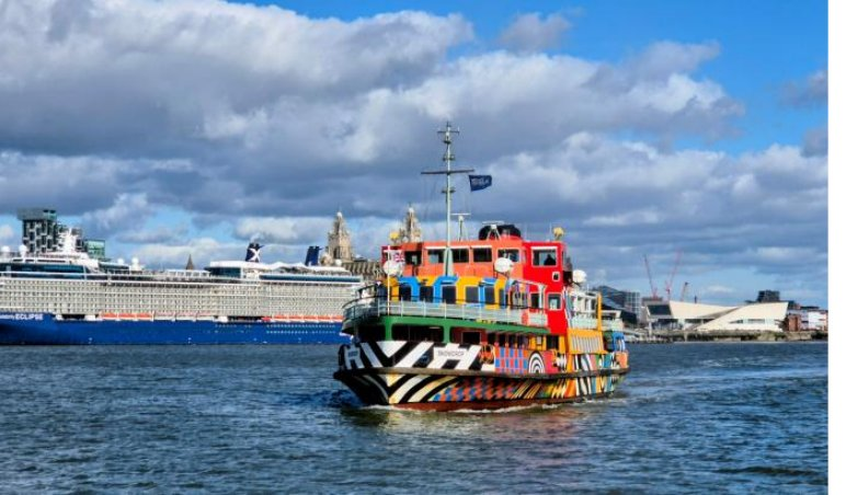 The Mersey ferry Snowdrop in a colourful dazzle paint scheme on the river, with a cruise ship behind